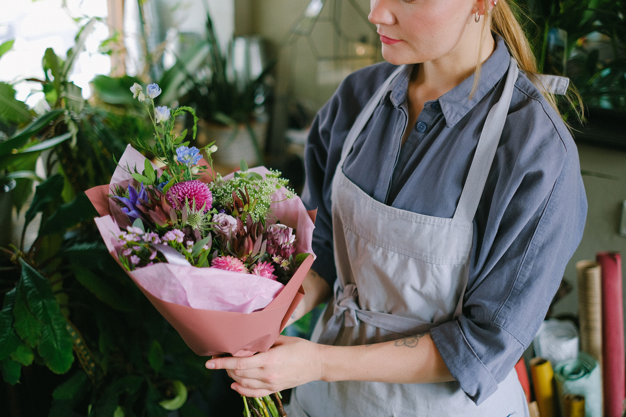 Woman in Blue Long Sleeve Shirt Holding Bouquet of Flowers